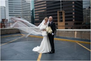 Woman's Club Minneapolis Wedding bride and groom in parking lot as veil blows in wind