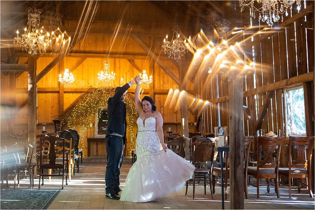 bride and groom dance in barn with lights